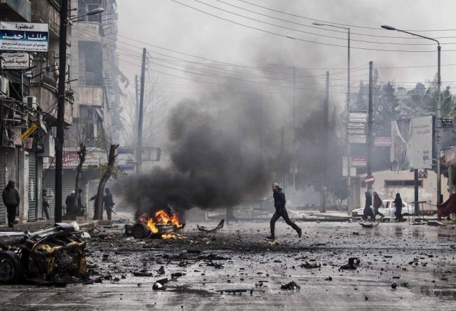 A man runs through the debris after a mortar shell hit a street.