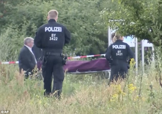 German police carry the body of the Afghan train attacker is carried from carriage and into a hearse after he was shot dead by police