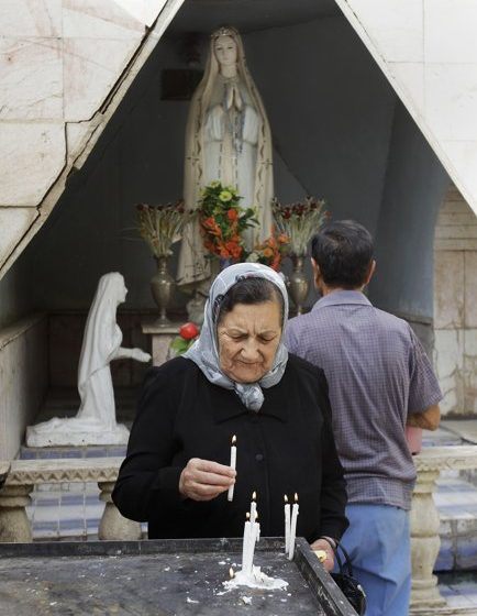  An Iraqi Christian woman lights candles at Virgin Mary Chaldean Church in Baghdad, Iraq.