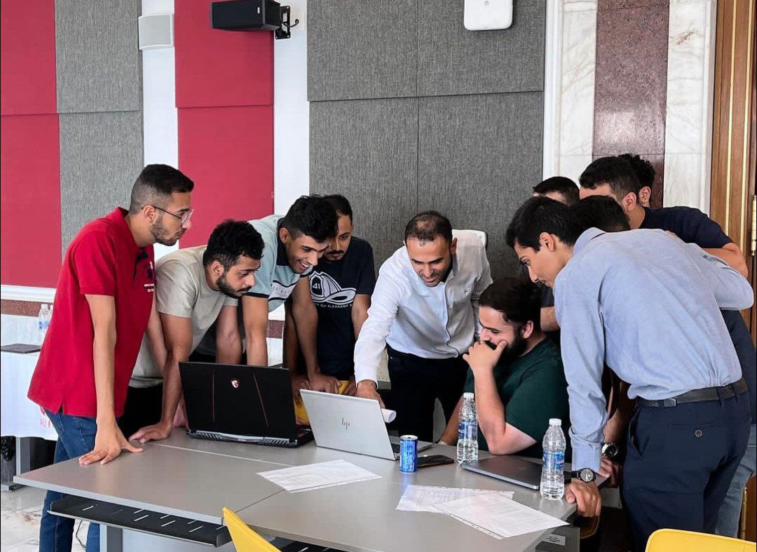 A group of students surrounding a professor who is explaining how to solve a certain computing problem